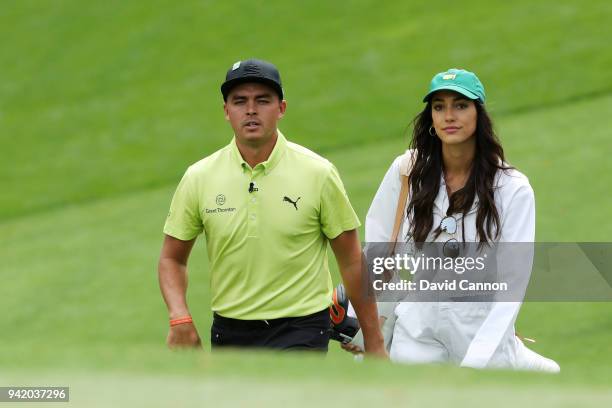 Rickie Fowler of the United States walks with girlfriend Allison Stokke during the Par 3 Contest prior to the start of the 2018 Masters Tournament at...