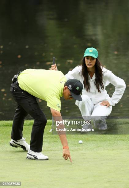 Rickie Fowler of the United States talks with girlfriend Allison Stokke during the Par 3 Contest prior to the start of the 2018 Masters Tournament at...