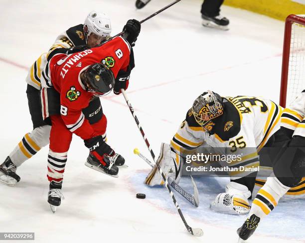 Anton Khudobin of the Boston Bruins stops a shot by Nick Schmaltz of the Chicago Blackhawks as Matt Grzelcyk applies pressure at the United Center on...