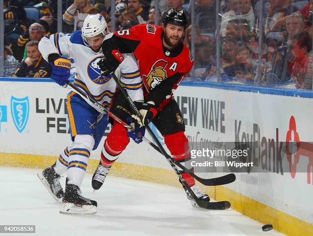 Marco Scandella of the Buffalo Sabres and Zack Smith of the Ottawa Senators battle for the puck along the boards during an NHL game on April 4, 2018...