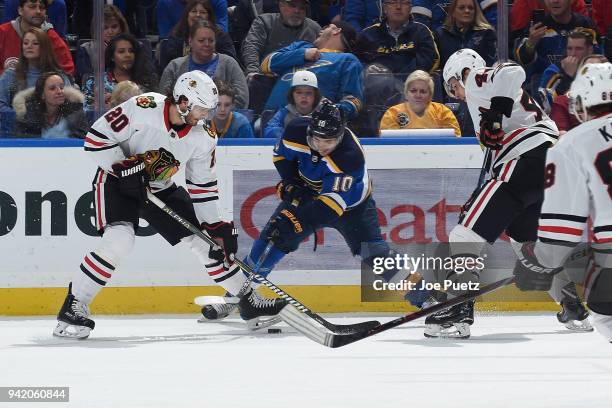 Brandon Saad of the Chicago Blackhawks and Brayden Schenn of the St. Louis Blues battle for the puck at Scottrade Center on April 4, 2018 in St....