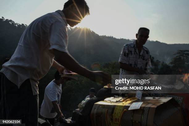 Ethnic Chinese Malaysian men throw paper money at their ancestor's grave at a cemetery during the annual Qingming festival in Karak, outside Kuala...