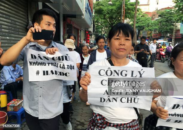 Protesters display placards as they march towards a courthouse during the trial of a prominent lawyer and five other activists in Hanoi on April 5,...