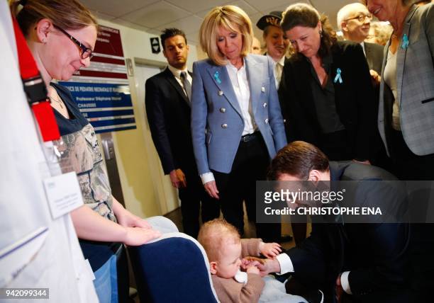 French President Emmanuel Macron talks to a baby as his wife Brigitte and French Health Minister Agnes Buzyn look on during a visit to the Rouen...