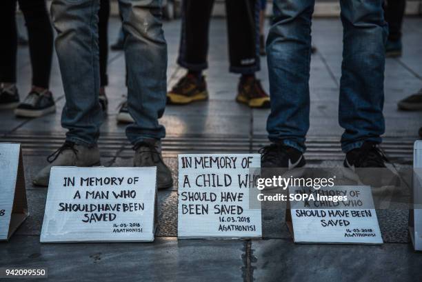 Small banners in front of the protesters, while they are standing. 16 refugees drowned when the small boat they were traveling on capsized near...