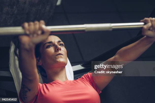 above view of determined sportswoman exercising bench press in a gym. - weight bench stock pictures, royalty-free photos & images
