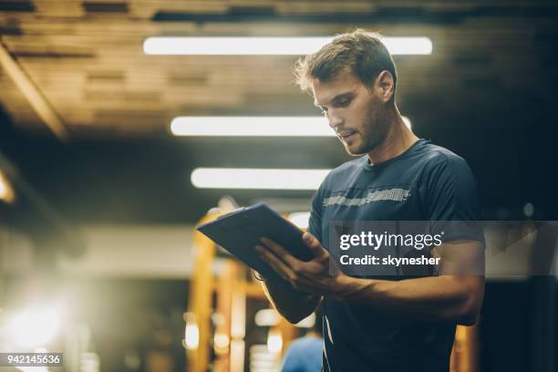 junge fitness-trainer einen trainingsplan in einem fitnessstudio zu lesen. - trainingsplan stock-fotos und bilder