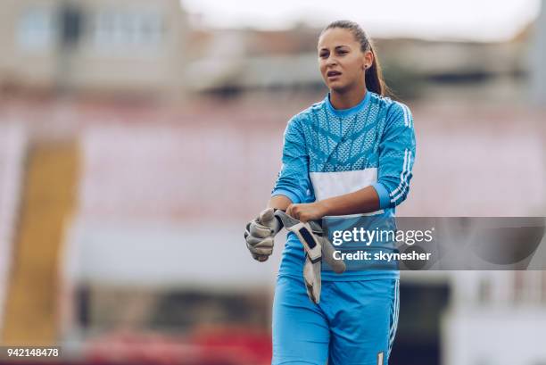 gardien féminin mettant sur ses gants avant le match au stade. - gants de sport photos et images de collection