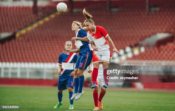 two female soccer rivals heading the ball on a match. - heading the ball stock pictures, royalty-free photos & images