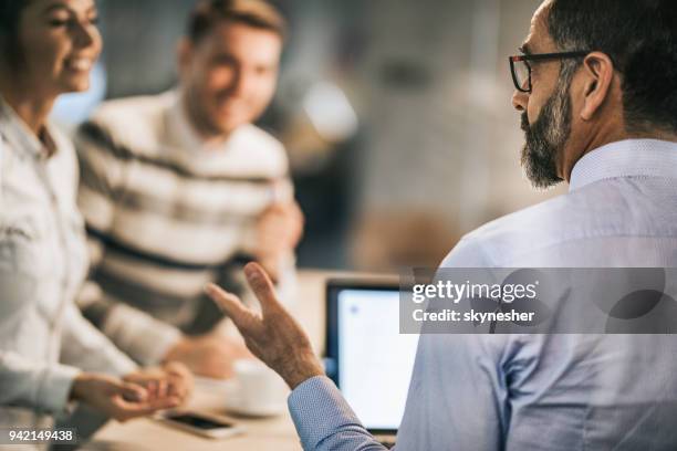 profile view of mature insurance agent talking to a couple in the office. - customer profile stock pictures, royalty-free photos & images