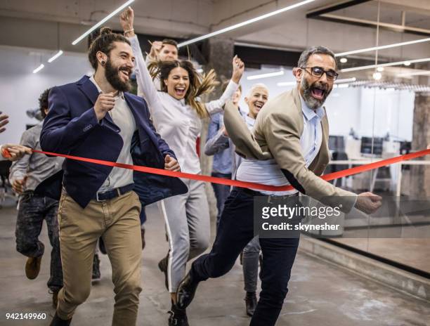 große gruppe von fröhlichen unternehmer spaß auf ein rennen im büro. - ziel stock-fotos und bilder