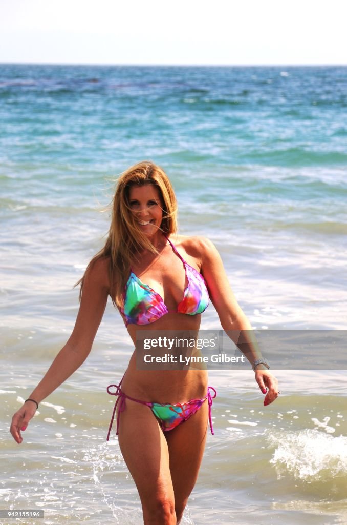 A fit beautiful woman stands on the beach in Malibu in her floral bikini