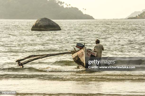 fisherman standing next to his fishing boat - palolem beach stock pictures, royalty-free photos & images