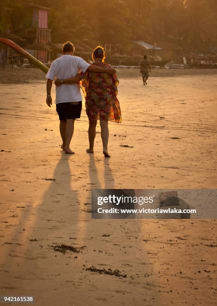 tourist couple walking along palolem beach - palolem beach stock pictures, royalty-free photos & images