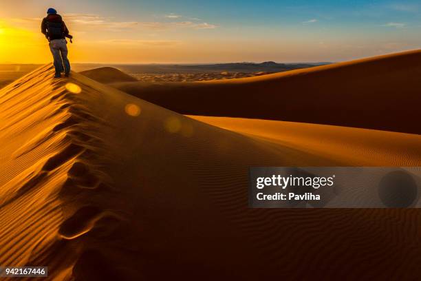 エルグ チェビ砂丘、モロッコ、北アフリカで日の出を楽しんでいる男 - sahara　sunrise ストックフォトと画像