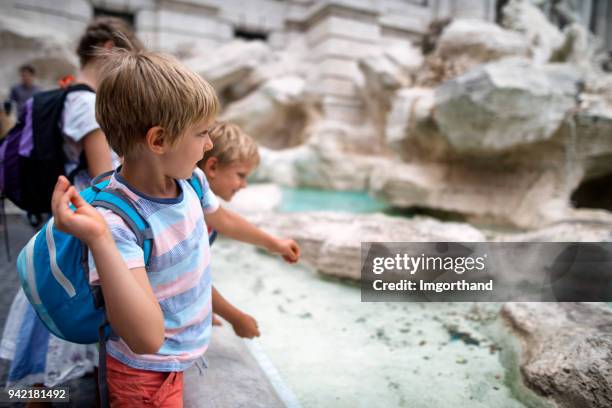 kids tourists throwing coins into trevi fountain, rome - coin fountain imagens e fotografias de stock