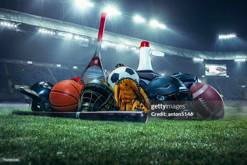 Sports balls on the field with yard line. Soccer ball, American football and Baseball in yellow glove on green grass. Outdoors