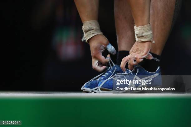 Ianne Guinares of New Zealand unties his shoelaces after his last lift during the Weightlifting Men's 62kg Final on day one of the Gold Coast 2018...