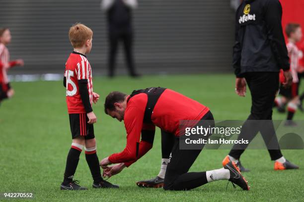 John O'Shea helps a under 9 players with his laces during a training session between the First Team and the under 9's at The Academy of Light on...