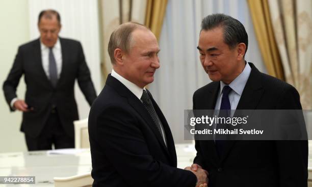 Russian President Vladimir Putin greets Chinese Foreign Minister Wang Yi as Russian Foreign Minister Sergey Lavrov looks during their talks at the...