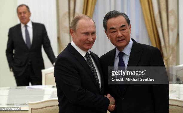 Russian President Vladimir Putin greets Chinese Foreign Minister Wang Yi as Russian Foreign Minister Sergey Lavrov looks during their talks at the...