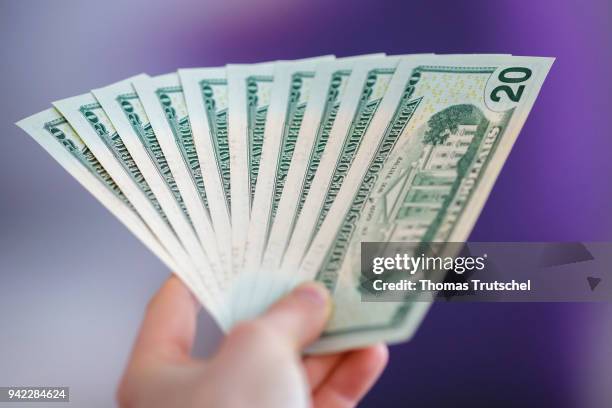 Berlin, Germany In this photo illustration a person is holding dollar bills in hand on April 05, 2018 in Berlin, Germany.