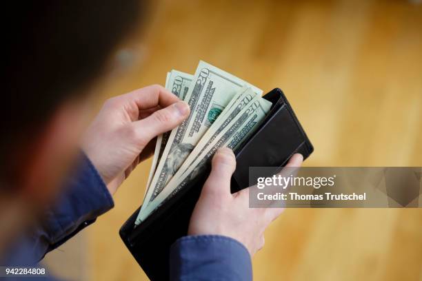 Berlin, Germany In this photo illustration a person hold a wallet, filled with Dollar bills on April 05, 2018 in Berlin, Germany.