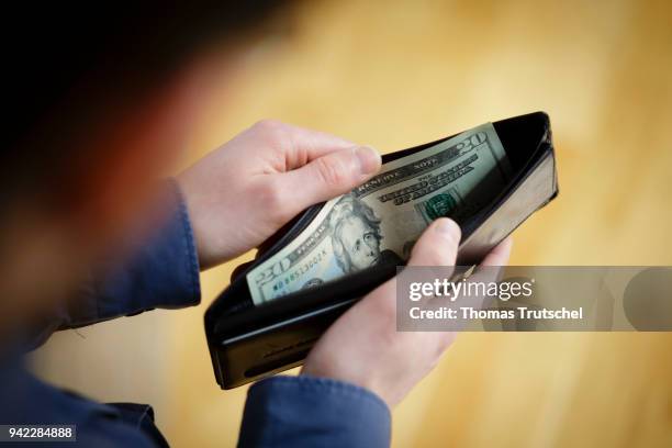 Berlin, Germany In this photo illustration a person hold a wallet, filled with Dollar bills on April 05, 2018 in Berlin, Germany.