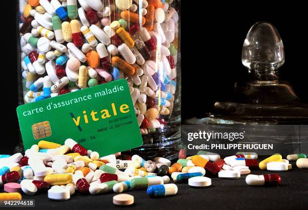 Picture taken on January 15, 2012 in Lille, northern France, of a "Carte vitale", French health insurance card set next to a jar containing drug...