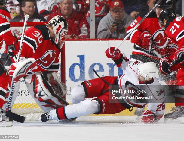 Goalie Martin Brodeur of the New Jersey Devils makes a save as Erik Cole of the Carolina Hurricanes slides into him in the second period of a hockey...
