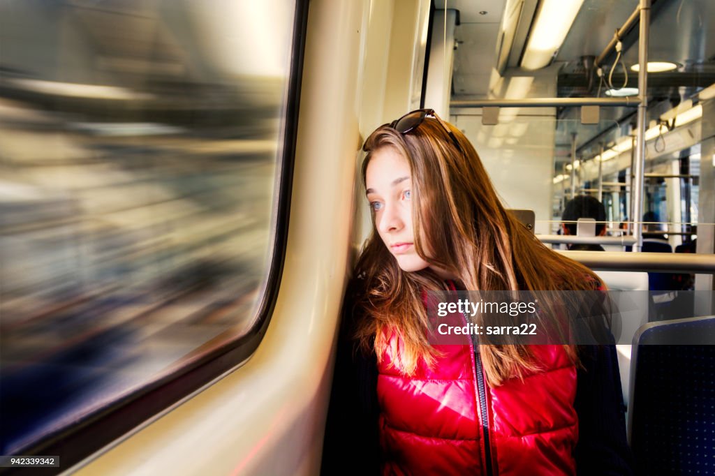 Young girl is looking thoughtfully trough the window.