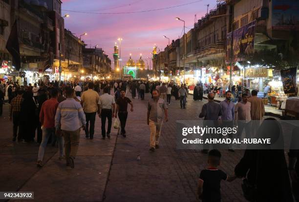 Iraqis walk near the shrine of the 8th century Shiite Imam Musa al-Kadhim in Baghdads northern district of Kadhimiya on April 5, 2018. - Fifteen...