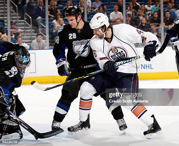 Zack Stortini of the Edmonton Oilers shoots the puck past Zenon Konopka and goaltender Mike Smith of the Tampa Bay Lightning during the second period...