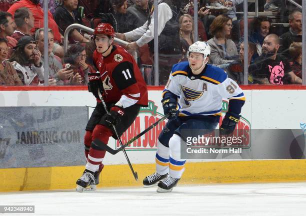 Brendan Perlini of the Arizona Coyotes skates up ice along side Vladimir Tarasenko of the St Louis Blues at Gila River Arena on March 31, 2018 in...