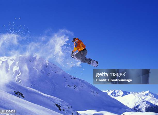 snowboarder in mid-jump with a cloud of snow trailing behind - boarding stock pictures, royalty-free photos & images