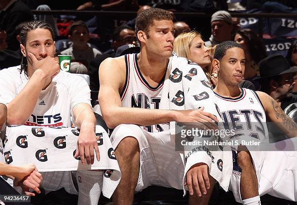 Josh Boone, Brook Lopez and Devin Harris of the New Jersey Nets sit on the bench during the game against the Dallas Mavericks on December 2, 2009 at...