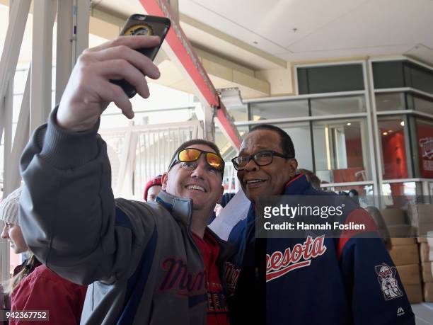 Hall of Fame player Rod Carew poses for a selfie with a fan as they enter the gates before the home opening game between the Minnesota Twins and the...