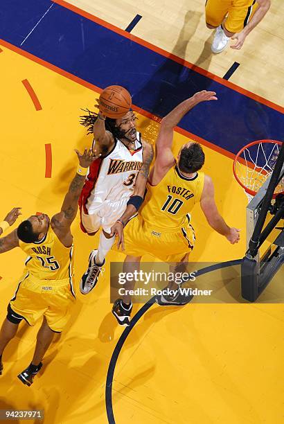 Mikki Moore of the Golden State Warriors shoots a layup against Brandon Rush and Jeff Fosger of the Indiana Pacers during the game at Oracle Arena on...