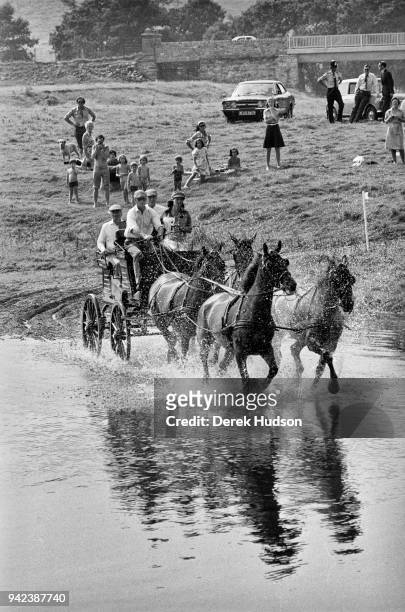Prince Philip, Duke of Edinburgh drives a team of four horses through the water during a carriage event, Penrith, England, July 1975. The other...