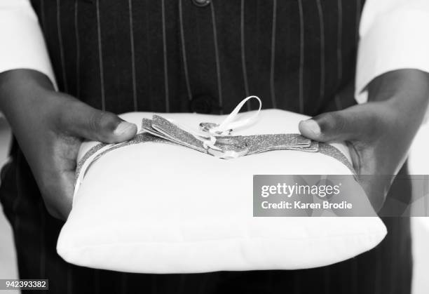 hands of ring bearer carrying pillow with wedding rings attached - ring bearer stockfoto's en -beelden