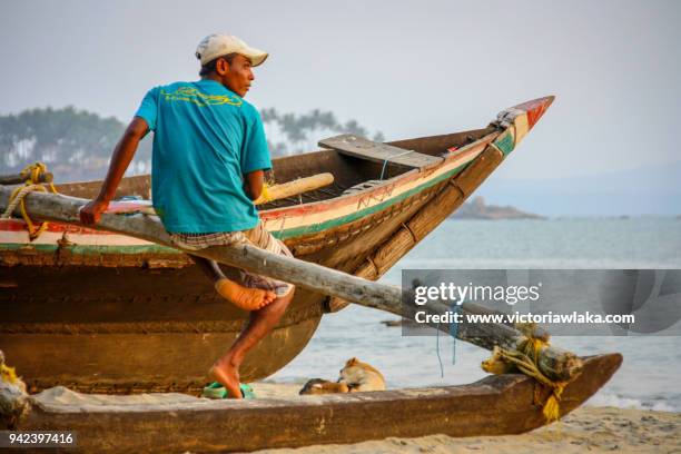fisherman sitting on the rim of his fishing boat - palolem beach stock pictures, royalty-free photos & images