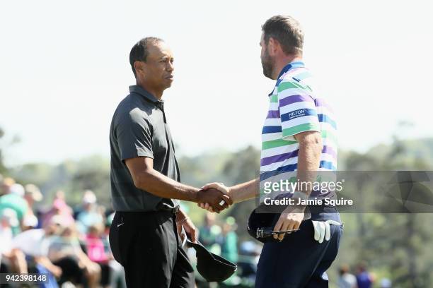 Tiger Woods of the United States shakes hands with Marc Leishman of Australia on the 18th green during the first round of the 2018 Masters Tournament...