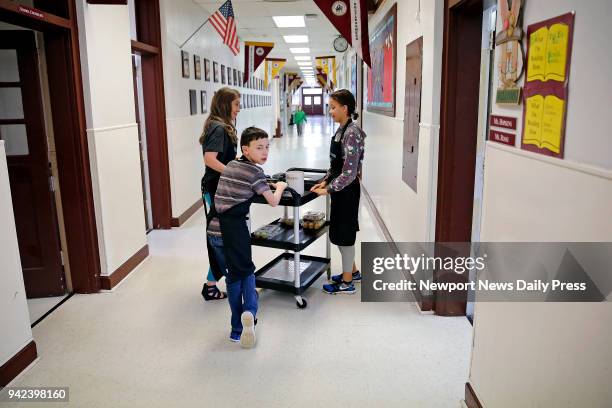 Shibuya, center, and Jasmine Baker deliver coffee with Lisa Esposito while working at Poquoson Middle School's Cool Beans Cafe on Thursday morning,...