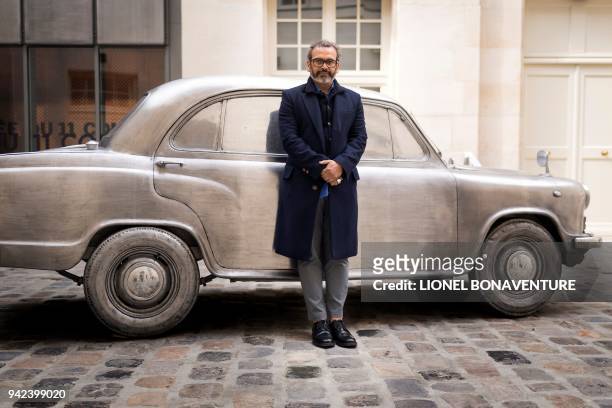 Indian artist Subodh Gupta poses next to one of his pieces at the Parisian museum La Monnaie de Paris during a photo session on April 5 in Paris. -...