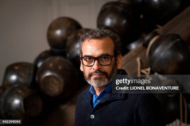 Indian artist Subodh Gupta poses next to one of his pieces at the Parisian museum La Monnaie de Paris during a photo session on April 5 in Paris. -...