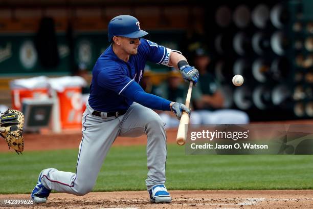 Ryan Rua of the Texas Rangers bunts for a fielders choice that scored two runs against the Oakland Athletics during the second inning at the Oakland...