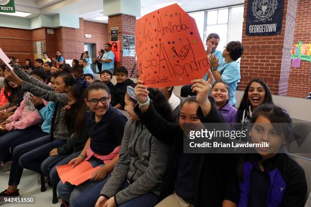 Students hold up signs for NASCAR Cup driver Aric Almirola during a suprise visit to announce the Lionel Racing "Design A Die-Cast" contest winner at...