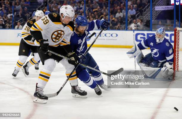 Anton Stralman of the Tampa Bay Lightning and Tim Schaller of the Boston Bruins battle for a loose puck during the third period of the game at the...