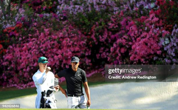 Tony Finau of the United States and caddie Gregory Bodine wait on the 13th green during the first round of the 2018 Masters Tournament at Augusta...