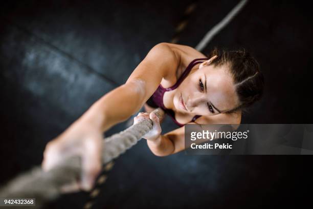 junge bergsteiger - woman climbing rope stock-fotos und bilder